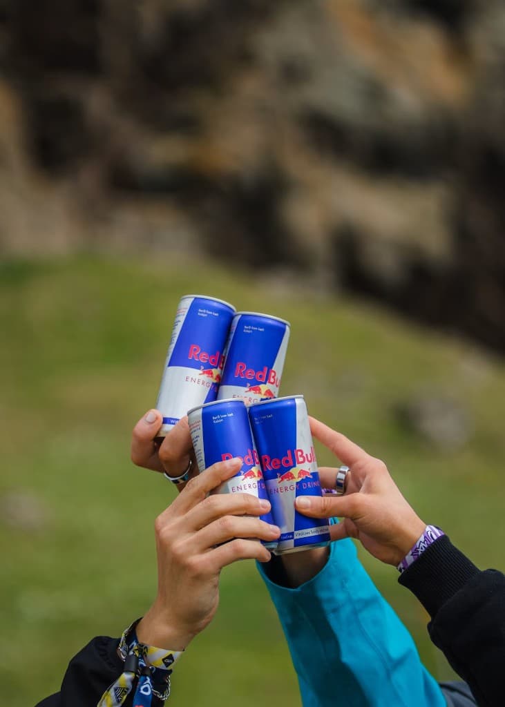 Manos brindando con latas en una experiencia al aire libre
